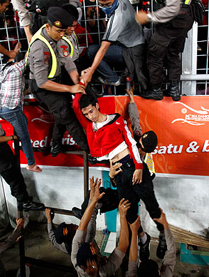 torcedora é retirada por policiais em confusão na partida da Malásia contra a Indonésia (Foto: AP)