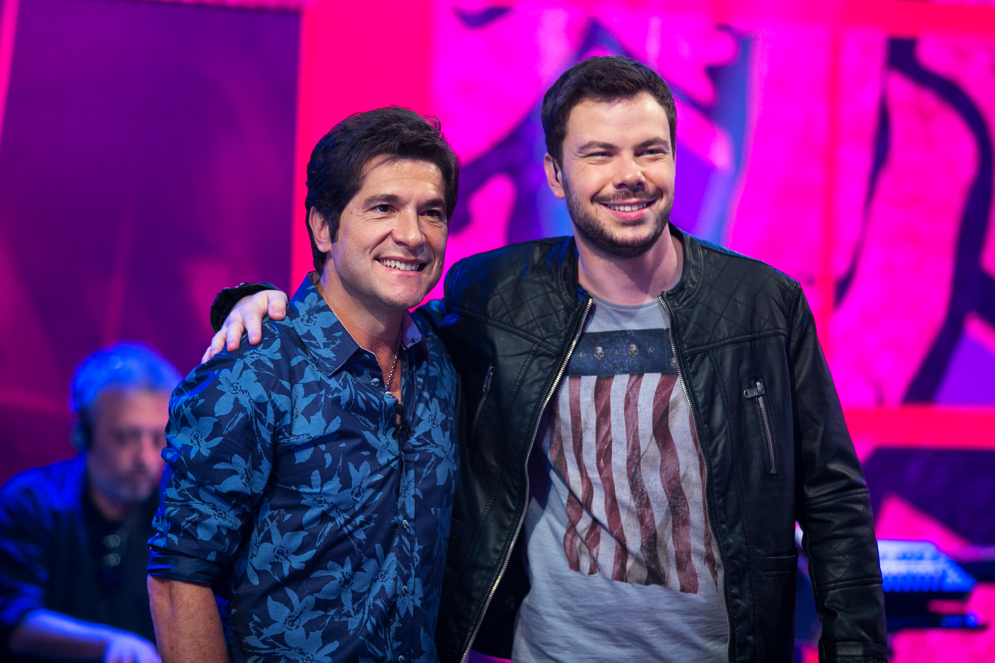 Nos estúdios do The Voice Brasil, Gustavo Trebien faz pose ao lado do técnico Daniel