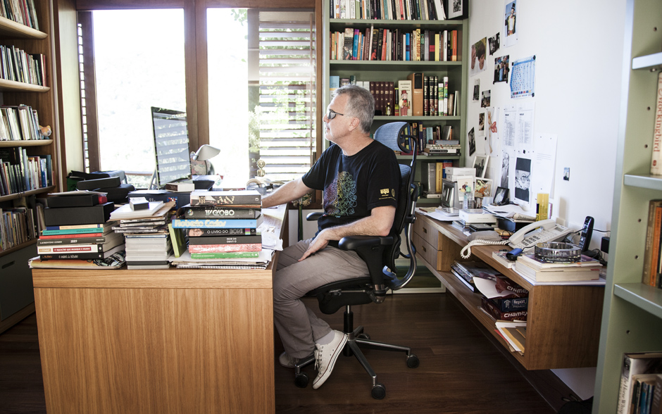Pedro Bial trabalha no seu escritório, rodeado de livros