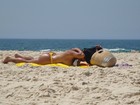 Solange Gomes tira a parte de cima do biquíni para se bronzear na praia