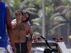 Ricardo Pereira dá mergulho no mar, enquanto a mulher fica no calçadão