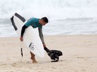 Cauã Reymond recolhe lixo da praia após surfar