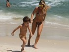 Com biquíni de oncinha, Livia Lemos brinca com o filho na praia