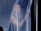 Acordada com fogos, Madonna espia atrás da cortina de janela do hotel