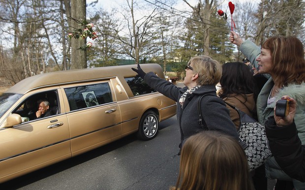 Fãs jogam flores no carro com o corpo de Whitney Houston no trajeto para o cemitério (Foto: Reuters)