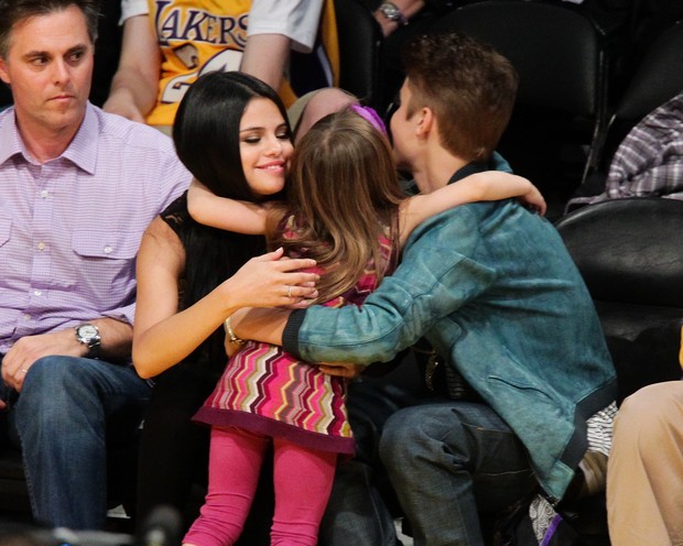 Justin Bieber e Selena Gomez abraçam fã-mirim em jogo de basquete (Foto: Getty Images)