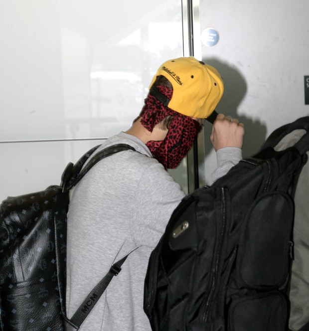 Justin Bieber se enconde dos paparazzi com boné e lenço no rosto (Foto: Grosby Group)