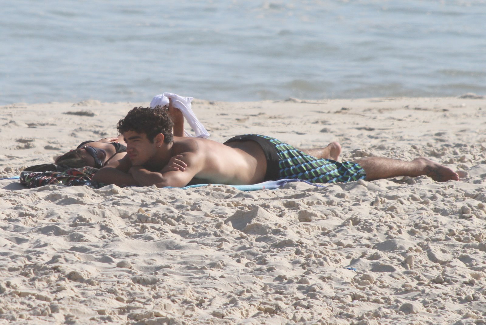 Caio Castro pegou sol nas costas enquanto conversava com sua companhia loira pela na praia da Barra