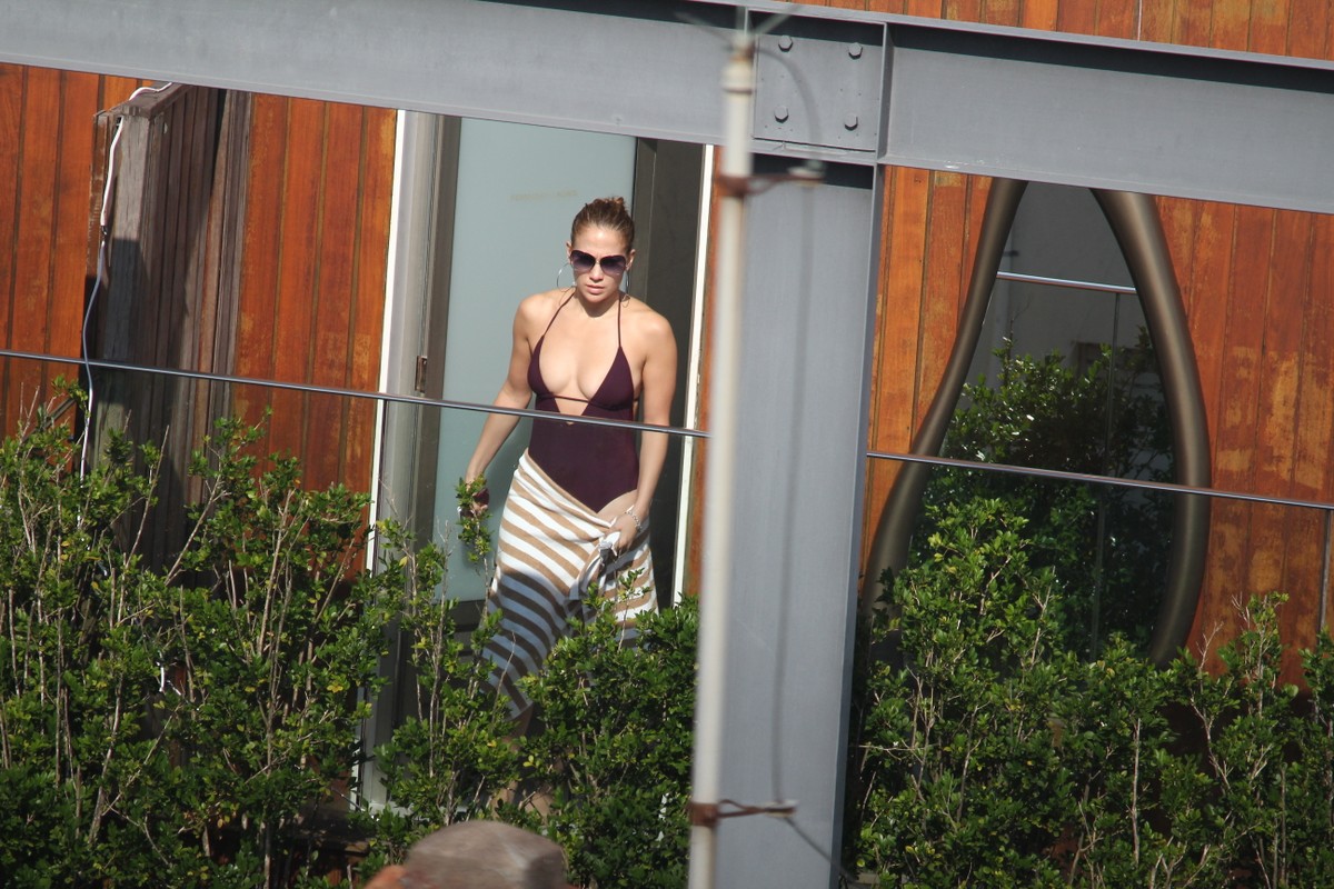 Jennifer Lopez escolheu um maiô superdecotado para curtir um dia de piscina em seu hotel no Rio.