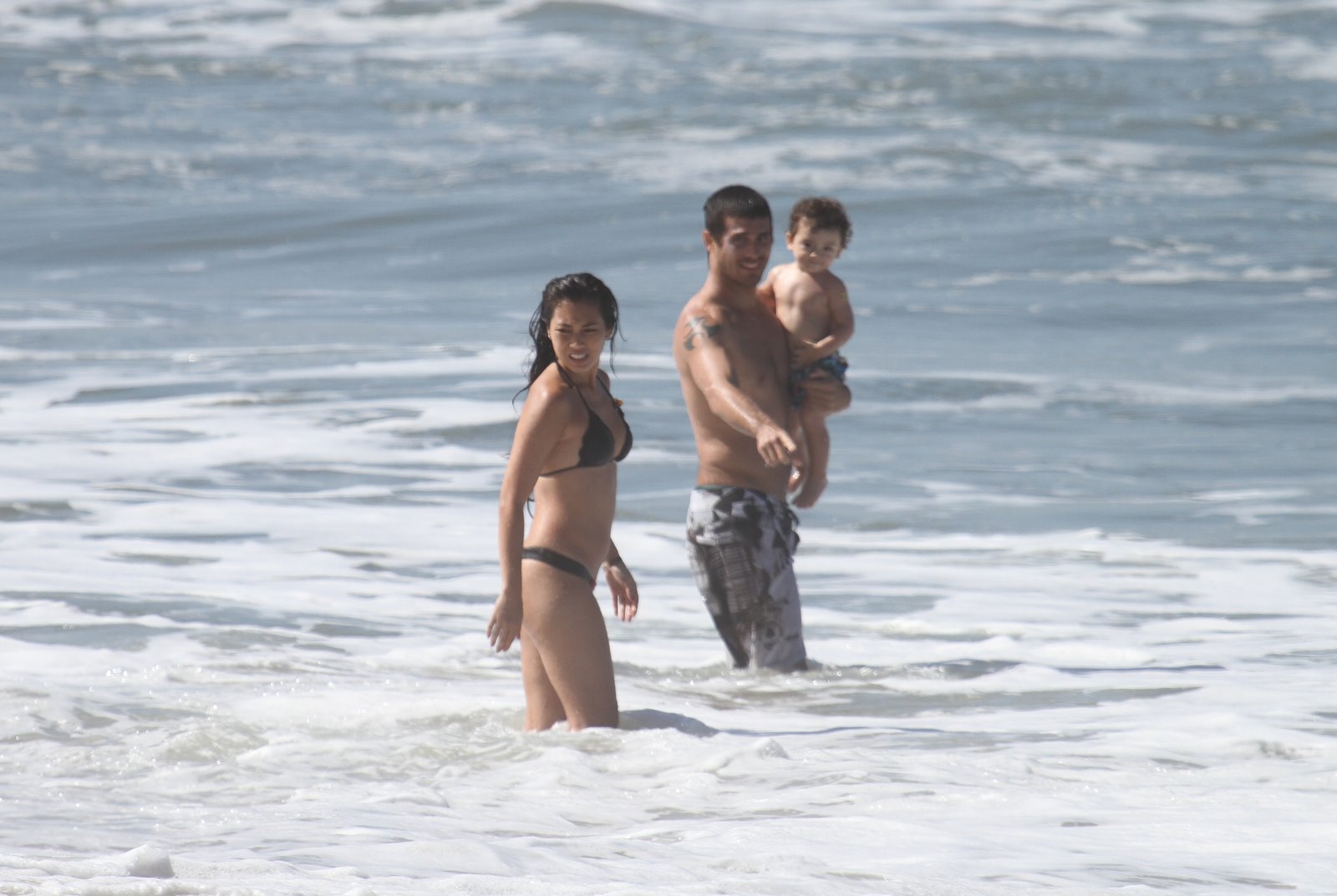 Daniele Suzuki no mar da Prainha, Zona Oeste do Rio, nesta sexta-feira, 3, com o marido, Fábio Novaes, e o filho, Kauai, de um ano
