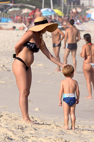 De biquíni, Danielle Winits exibe barriguinha na praia. Segundo a assessoria de imprensa, a atriz não está grávida. Na foto, ela ajeita o cabelo de Guy