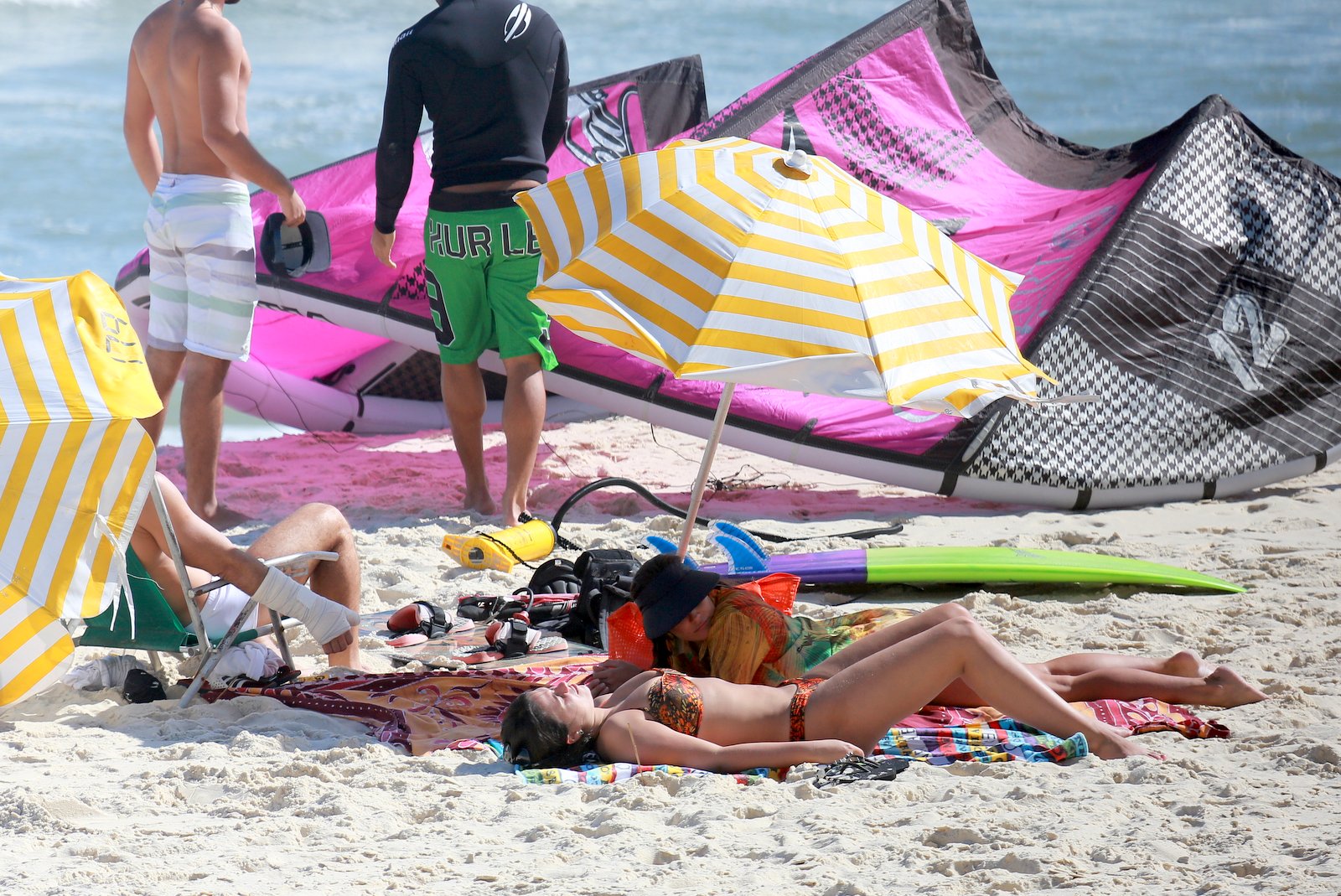 Grávida, Deborah Secco relaxa em praia, mas faz questão de se proteger do sol. 
