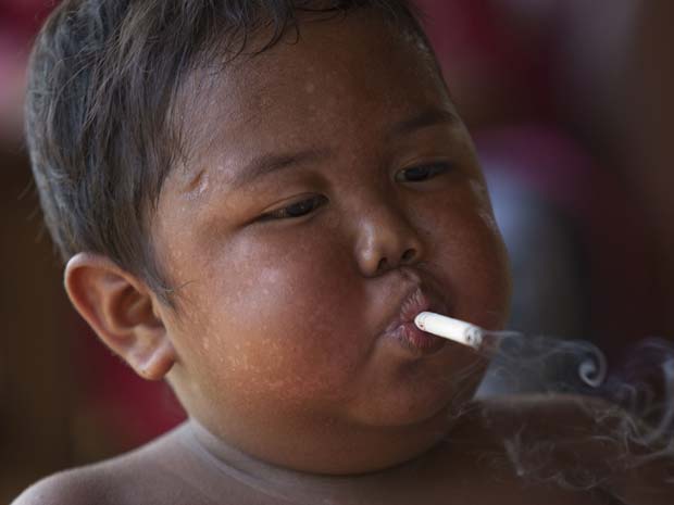 menino2Aldi SugandaRizal, de 2 anos, é visto fumando cigarro enquanto brica com parentes em 23 de maio, em Sekayu, distrito de Sumatra, na Indonésia. Segundo relatos da família, ele é viciado em cigarro e fuma 40 por dia. Ele começou a fumar aos 18 meses,