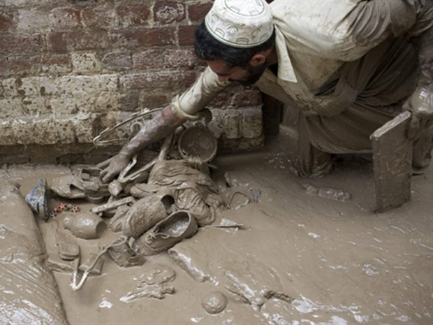Paquistanês recupera seus pertences após inundação em Nawshera, nesta segunda-feira (2)