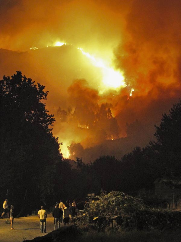 Pessoas observam fogo em Fornelos de Montes, noroeste da Espanha, nesta sexta-feira (13)