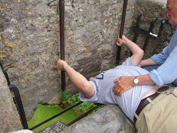 Pessoa beija a pedra Blarney, no castelo de mesmo nome, na Irlanda