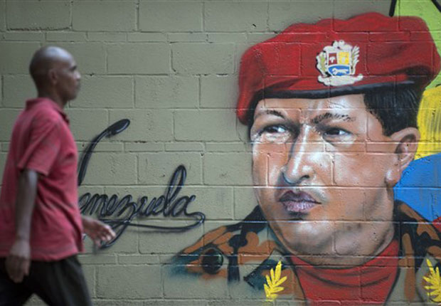 Venezuelano passa por cartaz com a figura do presidente Hugo Chávez nesta quinta-feira (23) em Caracas.