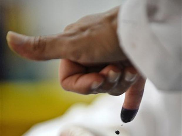 Eleitor molha o dedo com tinta durante o voto neste domingo (26) em Caracas.