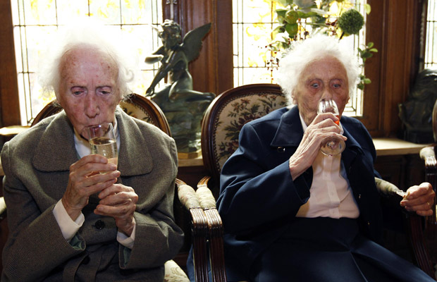 Gabrielle e Marie Vaudremer bebem champanhe neste sábado (2) em sua festa de 100 anos em casa de repouso em Château Sous-Bois.
