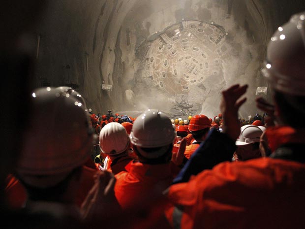Mineiros observam a perfuradora Sissi romper a rocha no fim do trecho Faido-Sedrun, no local da construção de um túnel em Gotthard, na Suíça.