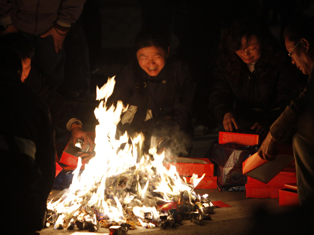 Moradores queimam pertences de seus parentes mortos nesta terça-feira (16) em Xangai, um dia após incêndio que matou 53 pessoas.