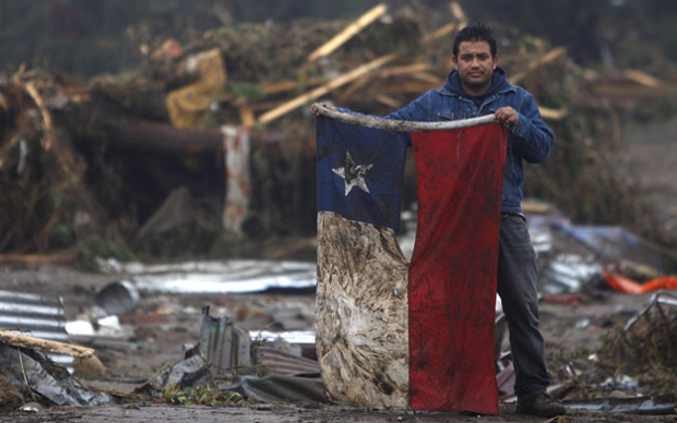Homem exibe a bandeira do Chile na cidade de Pelluhue, uma das regiões mais afetadas pelo terremoto em fevereiro deste ano.