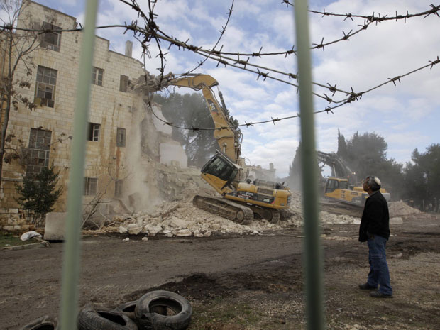 Trabalhador observa a demolição do Hotel Shepherd, em Sheikh Jarrah, Jerusalém Oriental, neste domingo (9).