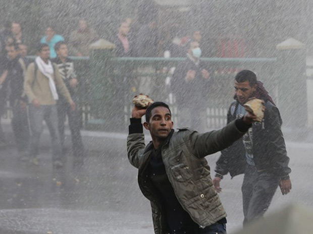 Manifestante egípcio atira pedras contra forças de segurança no Cairo.
