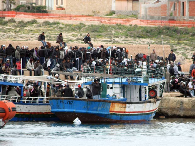 Imigrantes supostamente tunisianos chegam de barco à ilha siciliana de Lampedusa, na Itália, na sexta (11) (Foto: Elio Desiderio / AP)