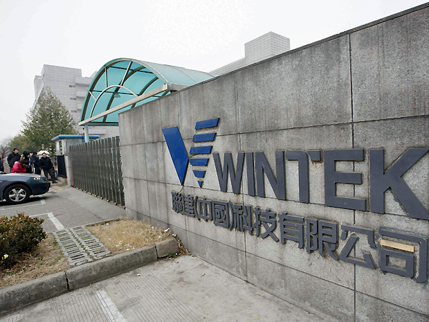 Pessoas em frete a uma fábrica de propriedade da Wintek, empresa taiwanesa que produz telas sensíveis ao toque para a Apple, em Suzhou, na província de Jiangsu, na sexta-feira (18). (Foto: Reuters)