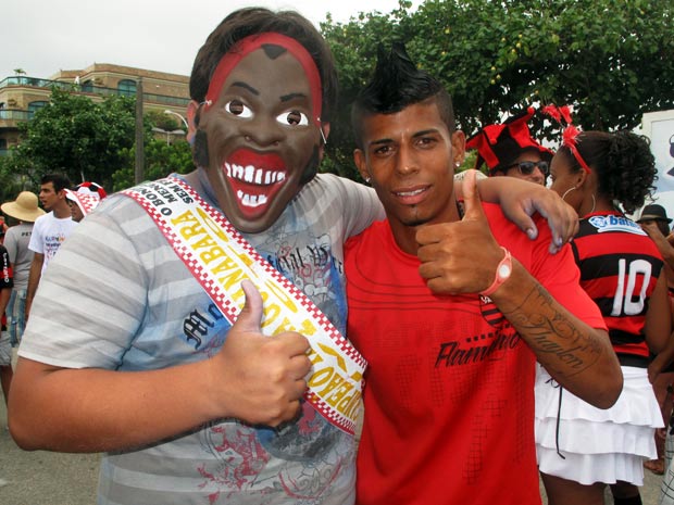 Um jovem com uma máscara do Ronaldinho e um jogador com o corte do cabelo do Léo Moura curtem o bloco. (Foto: Bernardo Tabak/G1)
