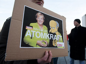 Manifestante segura cartaz com a chanceler alemã Angela Merkel e o personagem dos 'Simpsons' Sr. Burns, dono de uma usina de energia nuclear (Foto: John Macdougall/AFP)