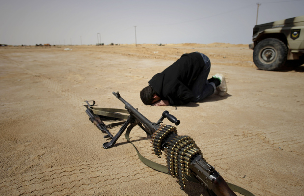 Rebelde ora no front de batalha próximo à cidade líbia de Brega nesta quarta-feira (6) (Foto: AP)