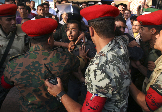 Soldados retiram manifestantes que bloqueavam rua na região da Praça Tahrir, no Cairo, nesta terça-feira (12) (Foto: AP)