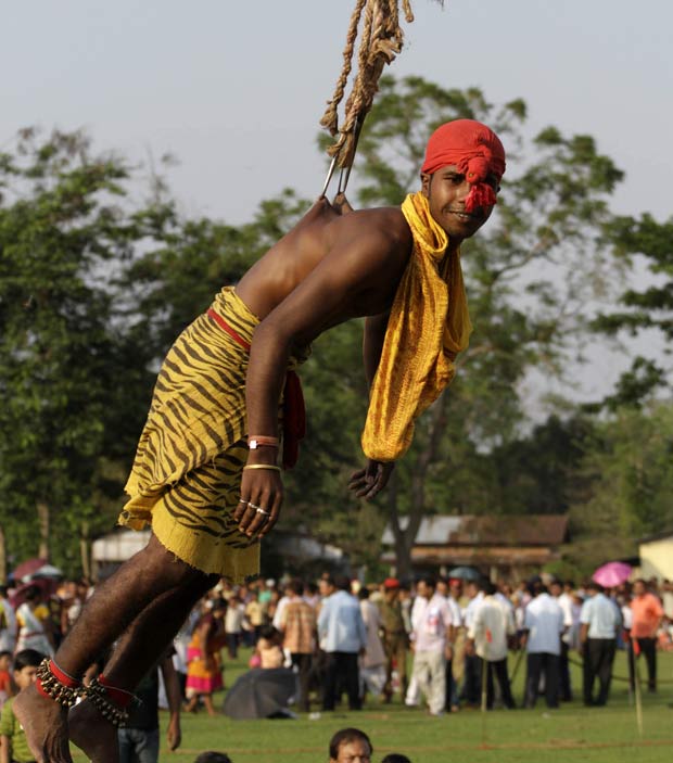 Indiano fica suspenso por ganchos cravados em suas costa na quarta-feira (20) durante as celebrações do festival Rongali Bihu em Boko, na Índia. (Foto: Anupam Nath/AP)