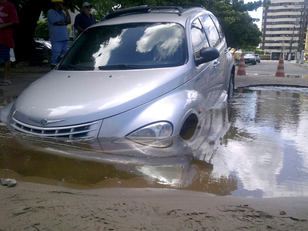 Veículo ficou parcialmente encoberto pela água de um buraco em rua de Maceió (Foto: Wanessa Oliveira/Gazetaweb.com)