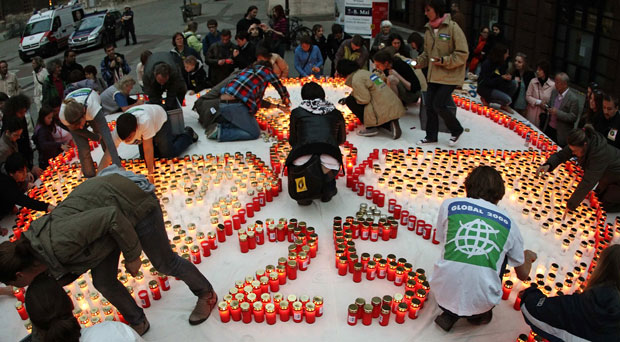Diversas pessoas ajudaram no arranjo das velas para montar o símbolo nuclear (Foto: Heinz-Peter Bader/Reuters)
