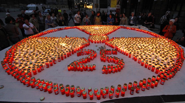 Manifestantes acenderam velas e formaram um enorme símbolo nuclear durante um protesto nesta segunda-feira (25) em Viena, na Áustria. O ato foi contra a produção de energia nuclear e lembrou os 25 anos do acidente nuclear de Chernobyl, na Ucrânia (Foto: Ronald Zak/AP)