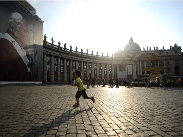 Praça São Pedro, com pôster do Papa João Paulo II, recebe visitantes na sexta-feira (29), dois dias antes da cerimônia de beatificação (Foto: Filippol Monteforte / AFP)