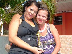 A atendente de telemarketing Andreza segura troféu de desempenho em vendas, ao lado da mãe, Joana:  ela já vendeu cartão de crédito até para irmã (Foto: Roney Domingos/ G1)