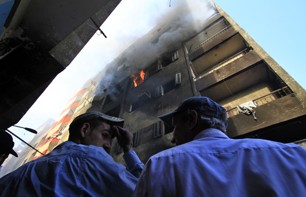 Policiais observam neste domingo (8) prédio em que moravam cristãos e que foram incendiados durante os confrontos da véspera em Imbaba, subúrbio do Cairo (Foto: AP)