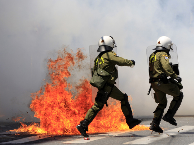 Policiais desviam de incêndio causado por bomba caseira em Atenas nesta quarta-feira (11) (Foto: Reuters)