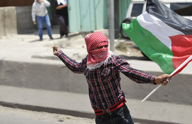 Palestino atira objeto contra as forças de segurança israelenses no posoto de controle de Qalandiya, próximo a Ramallah, na Cisjordânia (Foto: Darren Whiteside/Reuters)