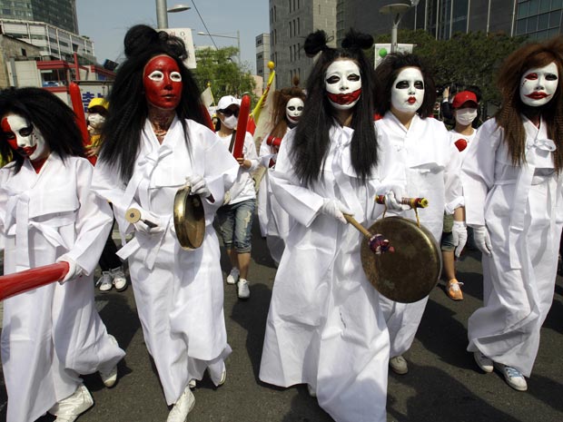 Antes de ameaçarem se suicidar, mulheres fizeram passeata com as caras pintadas e vestindo branco, cor usada em funerais em países do Oriente (Foto: AP)