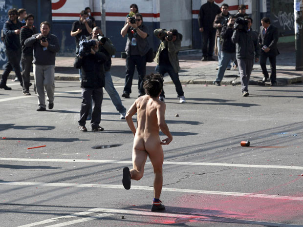 Manifestante corre nu durante protesto antigoverno no Chile neste sábado (21). Manifestação aconteceu nos arredores do Congresso, enquanto presidente Sebastian Piñera transmitia mensagem anual à nação (Foto: Ivan Alvarado/Reuters)