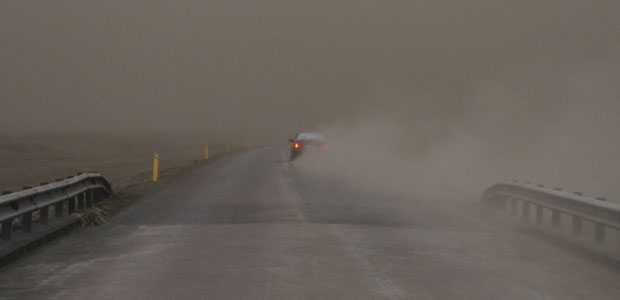 Carro passa por rodovia imerso na escuridão devido à precipitação de cinzas do vulcão (Foto: Ingolfur Juliusson/Reuters)