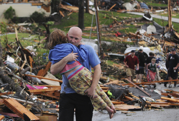 Homem socorre jovem garota que teve a casa atingida pelo tornado na cidade de Joplin (Foto: AP)