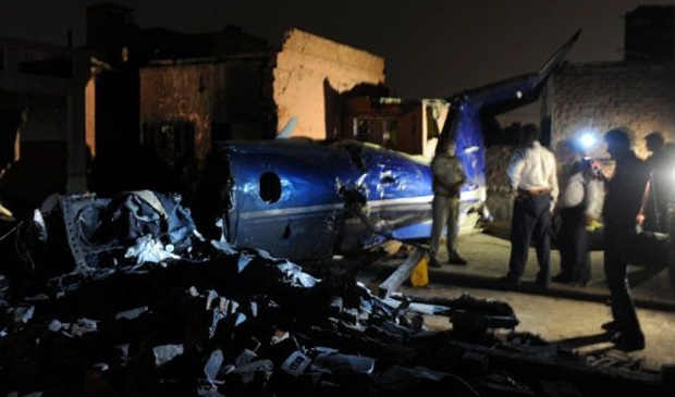 Moradores observam destroços de avião de pequeno porte que caiu sobre casa em Faridabad, cerca de 30 km de Nova Déli, na Índia (Foto: Prakash Singh / AFP)