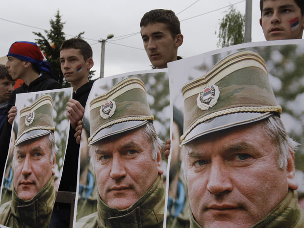 Jovens seguram cartazes com a foto de Ratko Mladic, em protesto contra sua prisão realizado por sérvios em Kalinovik, na Bósnia (Foto: AP)