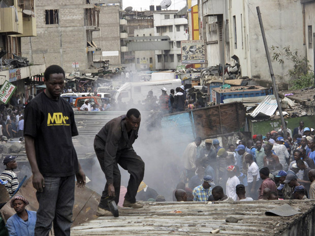 Moradores cercam local de explosão em área residencial de Nairóbi, capital do Quênia, neste domingo (5). Pelo menos 28 pessoas ficaram feridas, segundo a polícia. Aparentemente, uma explosão ocorreu em uma loja de ferragens, e o fogo espalhou-se atingindo bombas de um posto de combustível. Ainda não se sabia se o caso tinha relação com terrorismo. (Foto: AP)